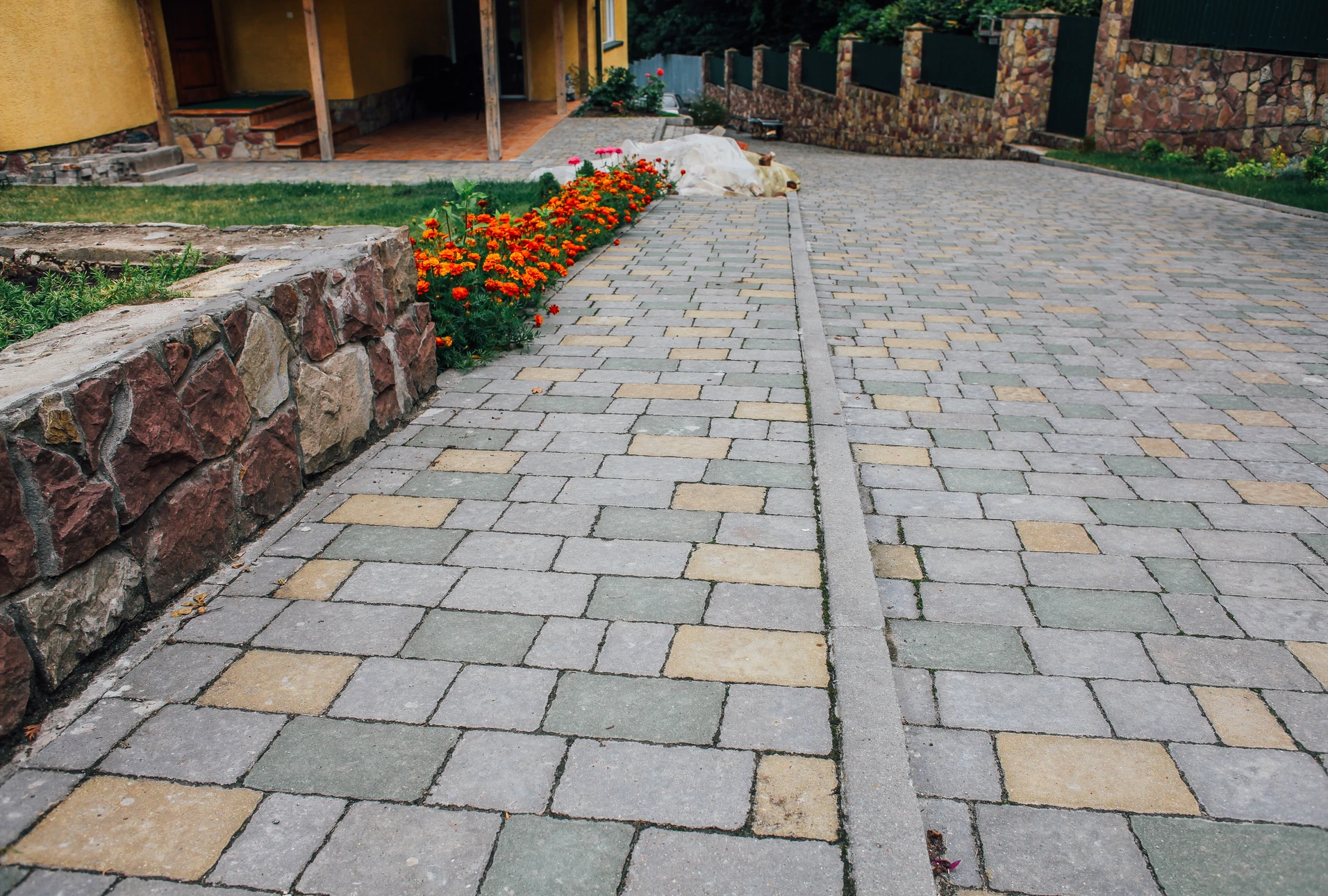 Ouvrier en tenue de travail installant un pavage extérieur, agenouillé sur chaussée en pavés de granite